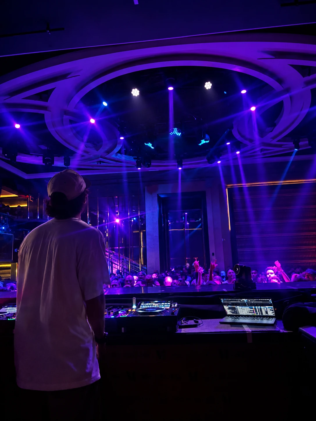 cutta performing at the DJ booth in front of a club crowd
